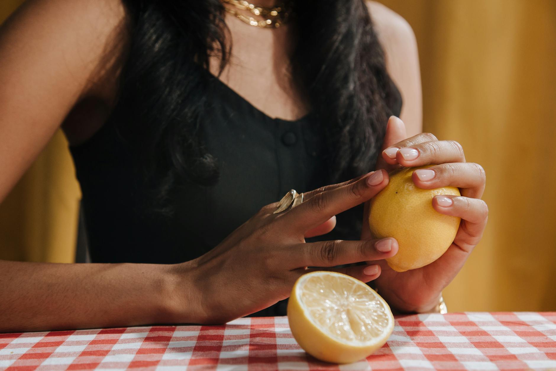 A hand holding a fresh lemon against a vibrant yellow background, representing renewed sensitivity and pleasure