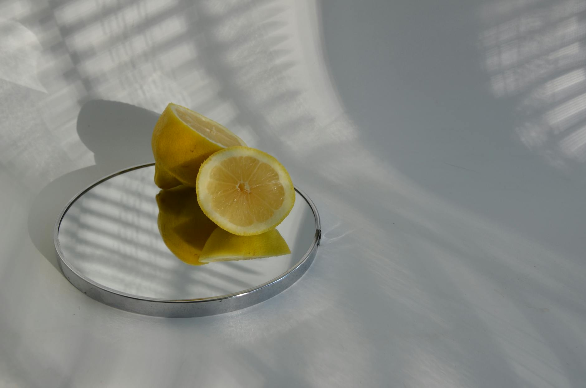 Hand holding a lemon on soft pink background surrounded by fresh lemons