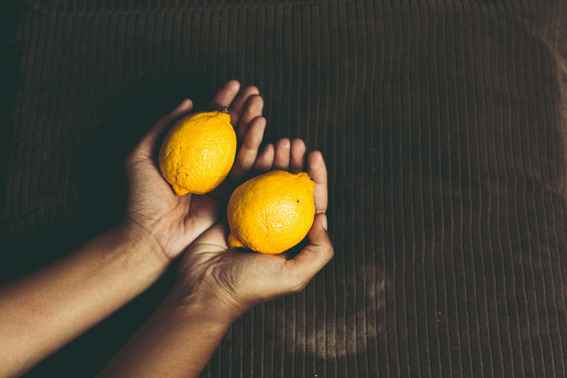 Close-up of fresh lemons held in cupped hands, symbolizing the natural design of the lemon vibrator