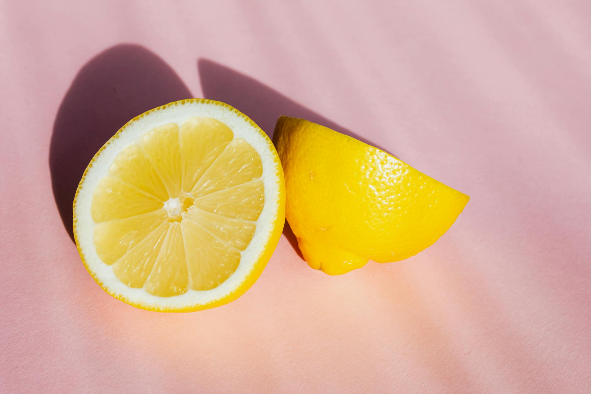Fresh lemon halves on a pink background in bright sunlight, symbolizing renewal and awakening