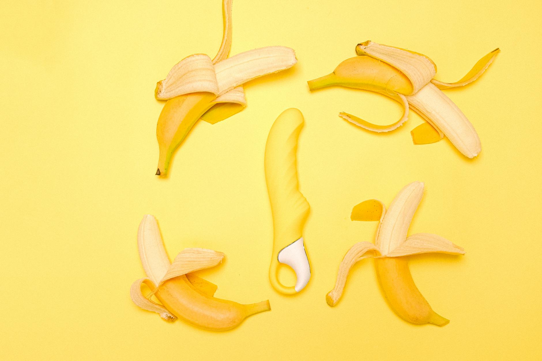 Yellow lemon-shaped clitoral vibrator arranged on a bright yellow background with fresh citrus