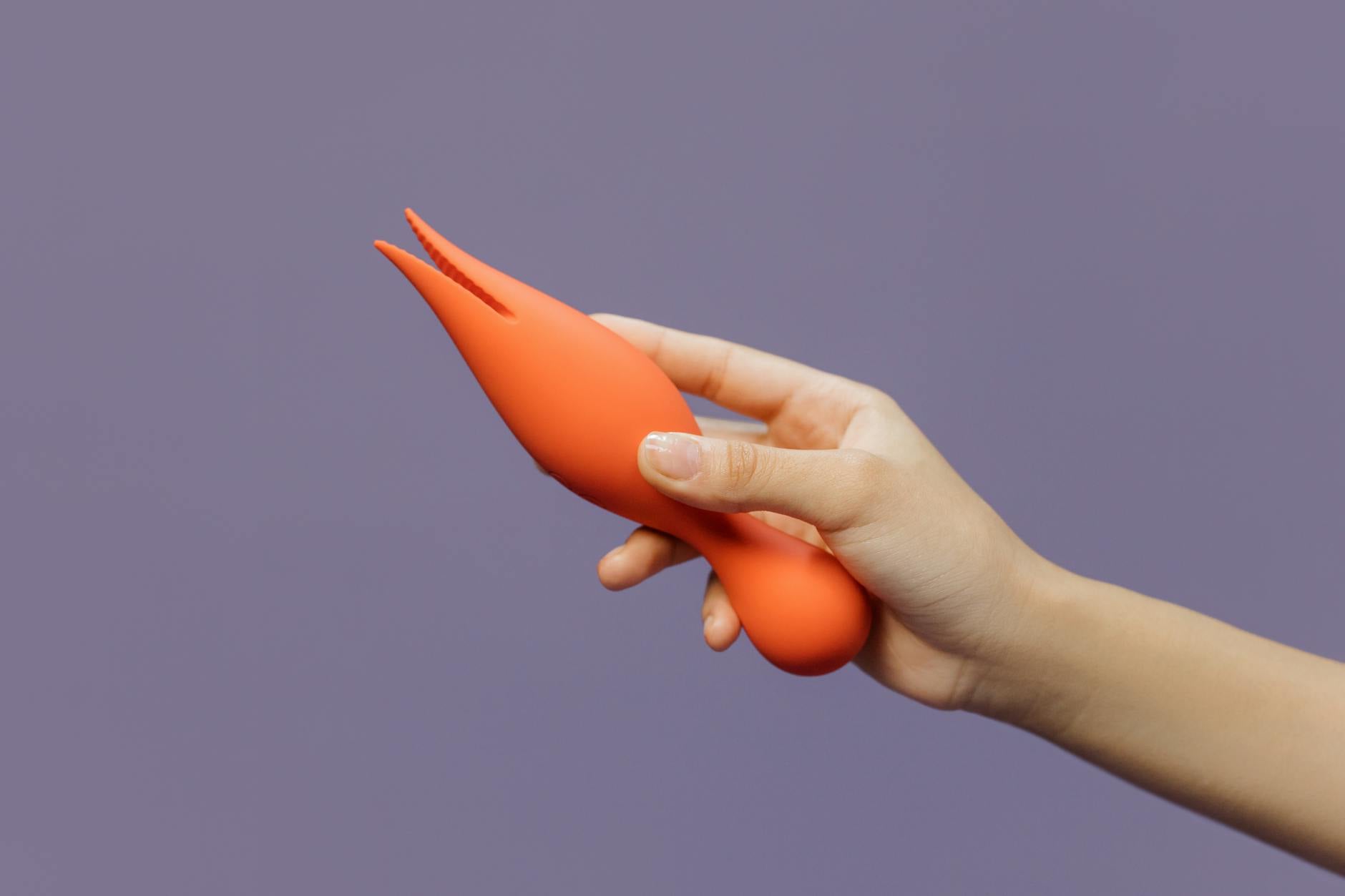 A close-up hand holding a lemon clitoral vibrator against a minimalistic backdrop, showcasing modern sensuality for beginners