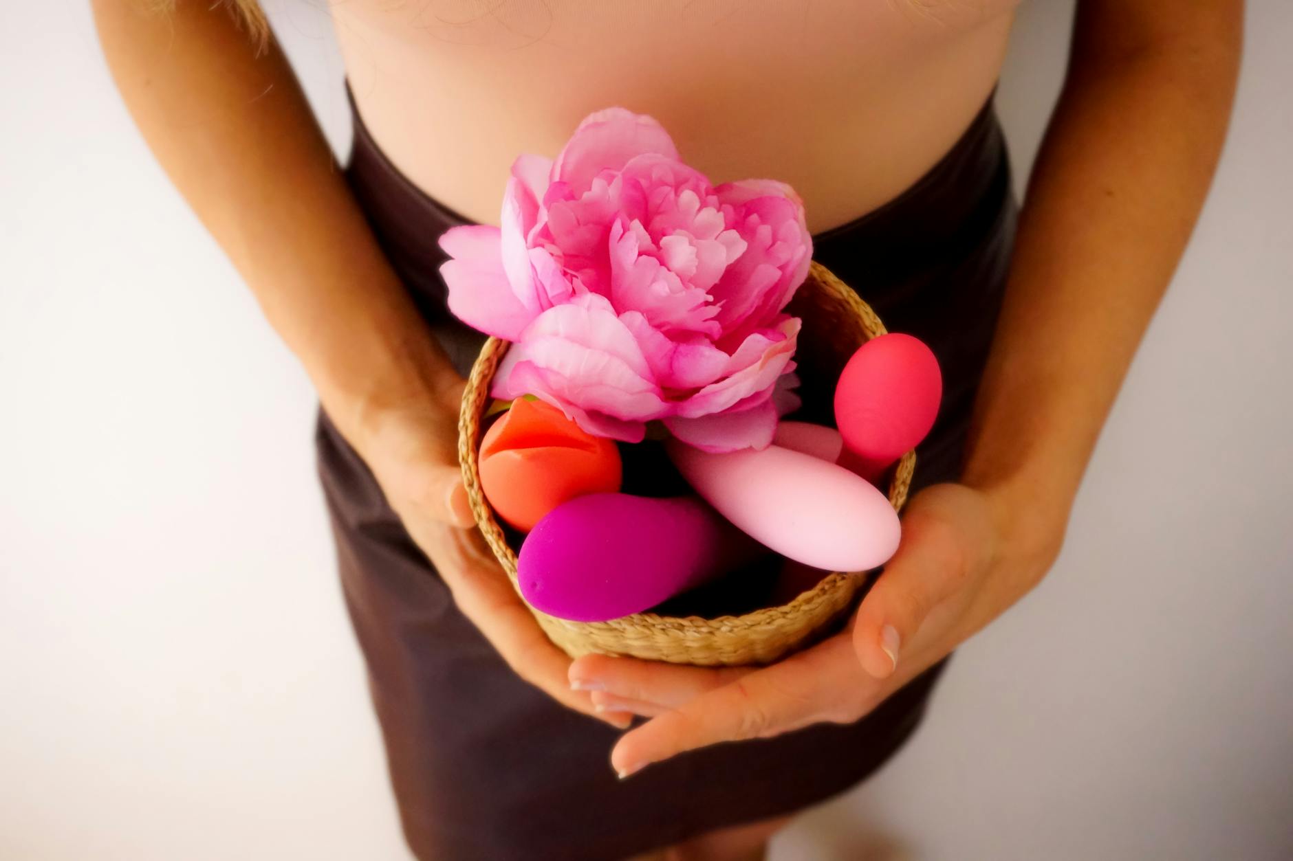A person holding a basket containing colorful lemon vibrators and intimate wellness products